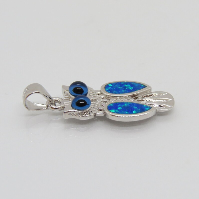 May include: Silver owl pendant with blue opal wings and blue evil eye details.