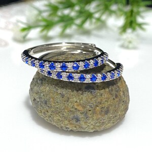 May include: A pair of silver hoop earrings with a double row of blue and white gemstones.