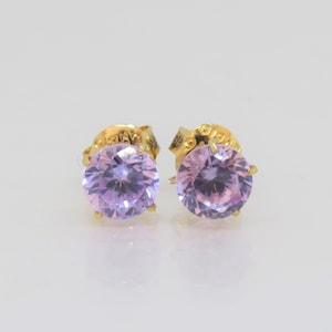 May include: A pair of gold stud earrings with round, light purple gemstones.
