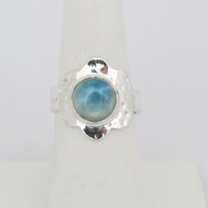 May include: A silver ring with a blue and white gemstone set in a flower-shaped setting.