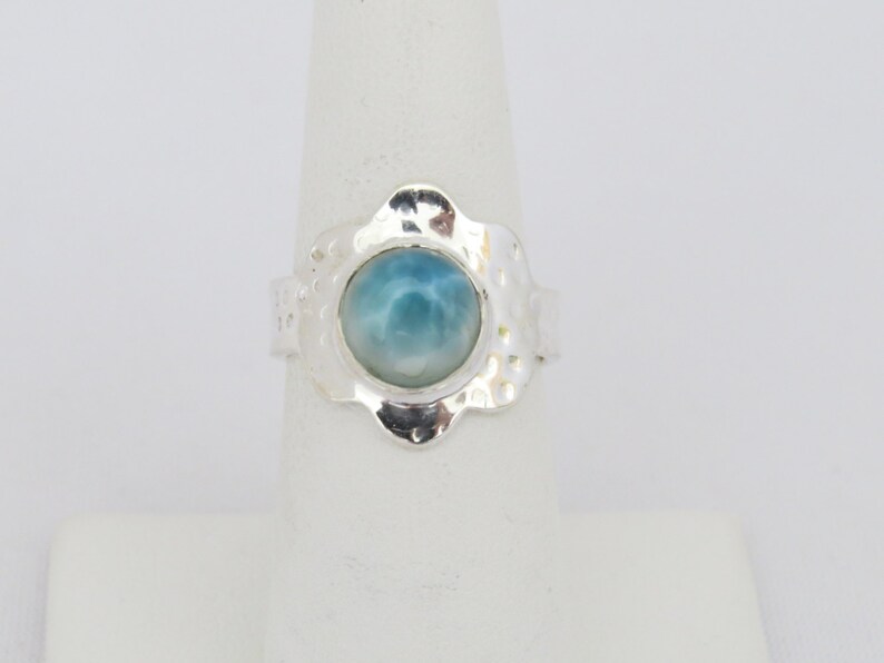 May include: A silver ring with a blue and white gemstone set in a flower-shaped setting.