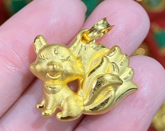 May include: A gold pendant in the shape of a cartoon fox with a curled tail. The pendant is detailed with a smiling face and small feet.