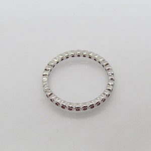 May include: A silver band ring with a row of small pink gemstones.