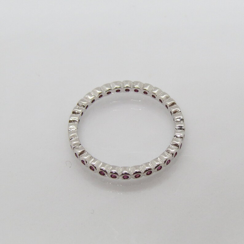 May include: A silver band ring with a row of small pink gemstones.