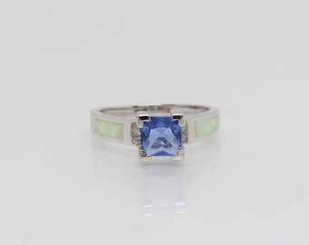 Può includere: Un anello d'argento con una pietra preziosa quadrata blu e due accenti di opale bianco.