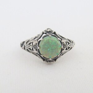 Pode incluir: Um anel de prata com um design ornamentado que apresenta uma pedra de opala verde.