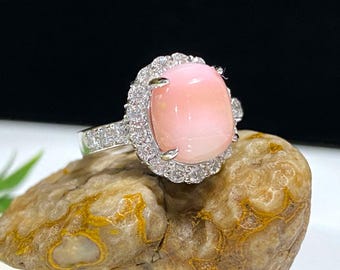 May include: A silver ring with a large pink gemstone surrounded by smaller clear gemstones.