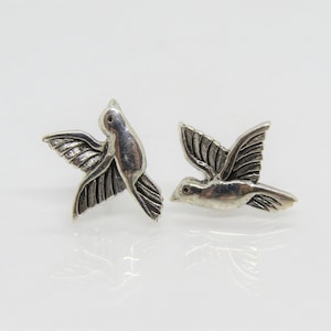 May include: A pair of silver dove earrings. The doves are in flight with their wings spread out.