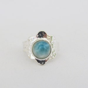 May include: A silver ring with a blue and white cabochon gemstone set in a flower-shaped design.
