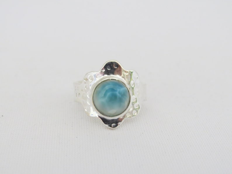 May include: A silver ring with a blue and white cabochon gemstone set in a flower-shaped design.