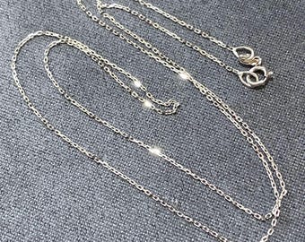 May include: A silver chain necklace with a delicate, linked design. The chain is layered and appears to be made of fine metal.