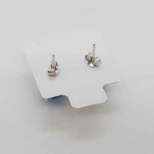Puede incluir: Un par de pendientes de plata con piedras azules. Los pendientes est&aacute;n sobre un fondo blanco.