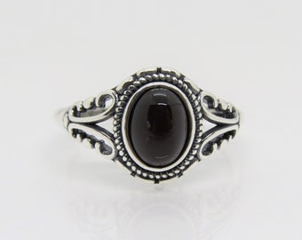 May include: A silver ring with an oval-shaped black gemstone set in a decorative filigree design.