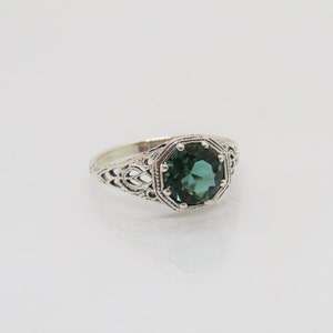 May include: A silver ring with an intricate filigree design and a large, octagonal, dark green gemstone.