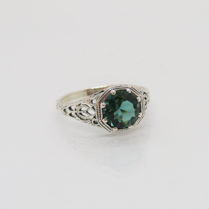 May include: A silver ring with an intricate filigree design and a large, octagonal, dark green gemstone.