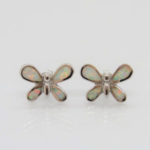 May include: A pair of silver butterfly earrings with iridescent white opal stones.