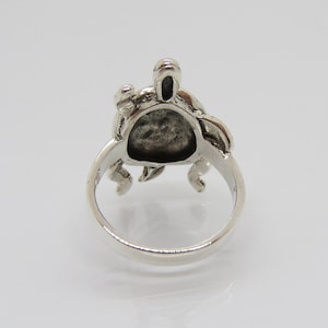 May include: Silver ring featuring a detailed turtle design. The turtle is facing forward with its head raised and its legs outstretched. The ring is made of sterling silver and has a polished finish.