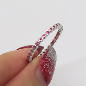 May include: A silver band ring with a row of small pink gemstones.