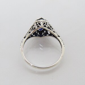 May include: A silver ring with a blue gemstone set in a filigree design.