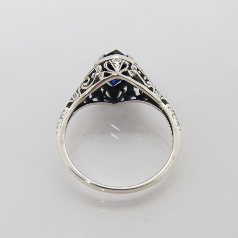 May include: A silver ring with a blue gemstone set in a filigree design.