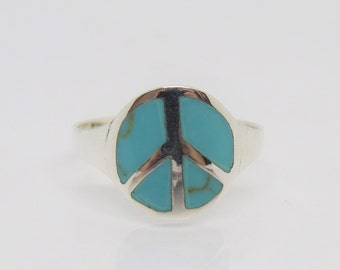 May include: A silver ring with a turquoise peace sign.