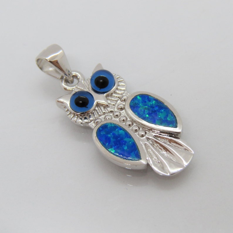 May include: Silver owl pendant with blue opal accents and black evil eye details.