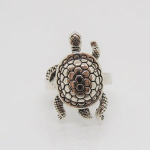 May include: A silver turtle ring with a detailed shell design. The ring is made of sterling silver and features a realistic turtle design.