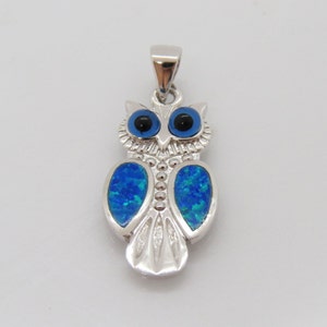 May include: Silver owl pendant with blue opal eyes and blue opal wings. The owl is a symbol of wisdom and good luck.