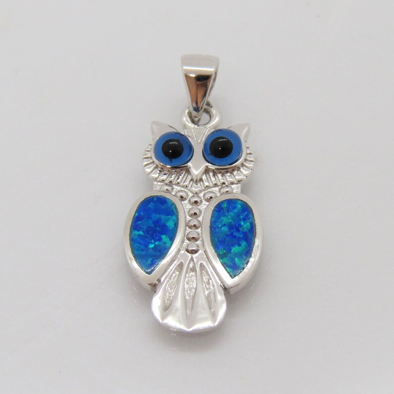 May include: Silver owl pendant with blue opal eyes and blue opal wings. The owl is a symbol of wisdom and good luck.