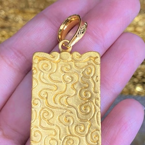 Pu&ograve; includere: Ciondolo in oro di forma quadrata con un motivo a spirale. Il ciondolo ha un anello in alto ed &egrave; contrassegnato dal numero "9999".