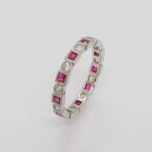 May include: A silver band ring with alternating square-shaped pink and white gemstones.