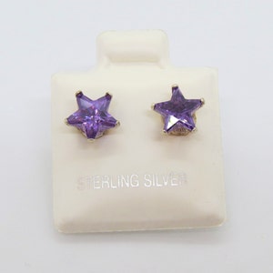 May include: A pair of sterling silver star stud earrings with purple cubic zirconia stones.