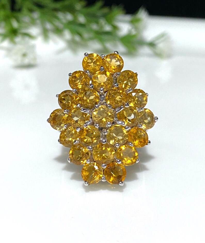 May include: A silver ring with a cluster of yellow gemstones set in a flower-like design.