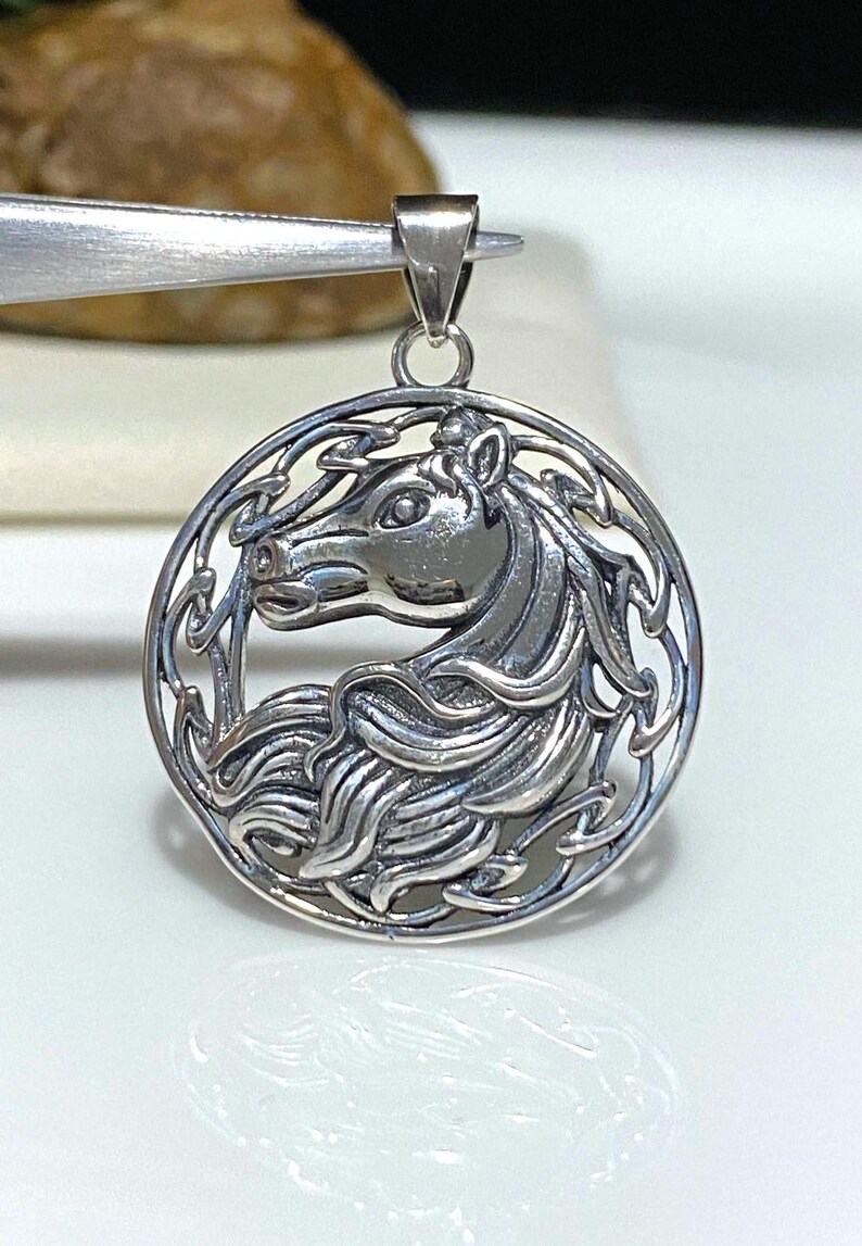 May include: Silver pendant featuring a detailed Celtic knot design with a horse's head in the center.