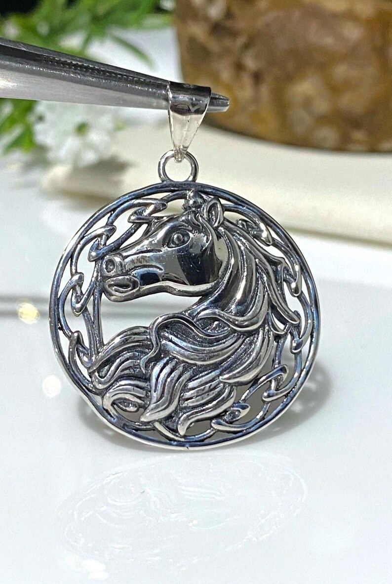 May include: Silver pendant featuring a detailed Celtic knot design with a horse's head in the center.