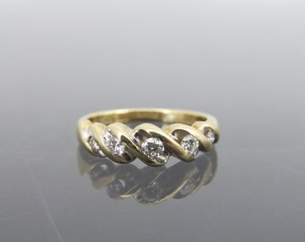 Puede incluir: Un anillo de banda de oro con un diseño retorcido y cinco diamantes redondos engastados en la banda.