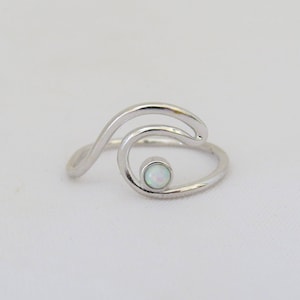 May include: A silver wave ring with a white opal gemstone in the center.