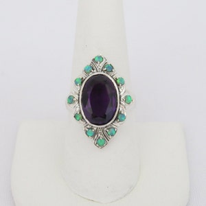 May include: A silver ring with a large oval amethyst gemstone surrounded by smaller green opal gemstones.