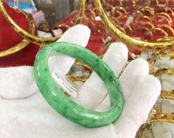 May include: A green jade bangle bracelet with a white tag that reads "NATURAL JADEITE" and "SIZE 112922".