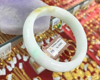 May include: A white jade bangle with green and yellow accents. The bangle is labeled "NATURAL JADEITE" and "PNJ No.11252".