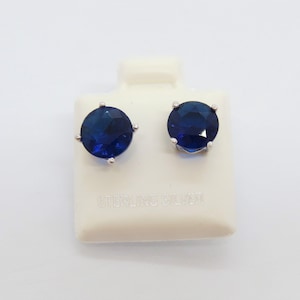 May include: A pair of sterling silver stud earrings with round, dark blue gemstones.