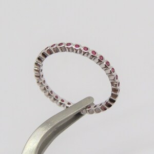 May include: A silver band ring with a row of small pink gemstones.