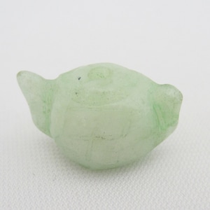 Könnte beinhalten: Eine kleine, hellgrüne Glas-Teekannenfigur. Die Teekanne hat einen runden Körper und einen kleinen Ausguss.