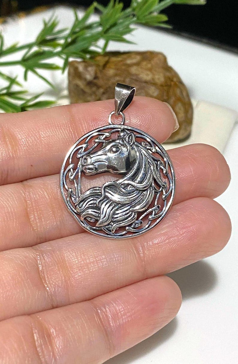 May include: Silver pendant featuring a detailed Celtic knot design with a horse's head in the center.