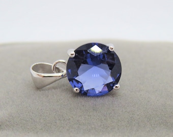 May include: A silver pendant with a large, round, dark blue gemstone.
