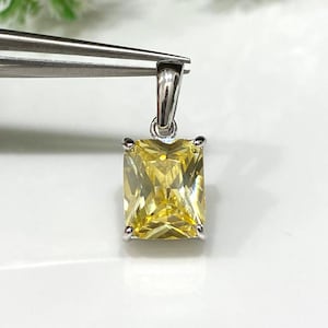 May include: A silver pendant with a yellow square-shaped gemstone.