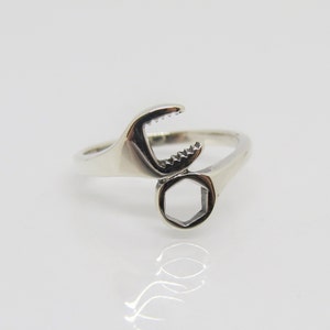 May include: A silver ring shaped like a wrench with a hexagonal opening.
