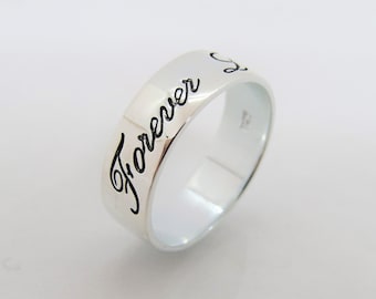 May include: A silver band ring with the inscription "Forever" in a cursive font.