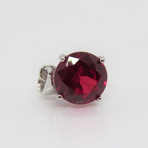 May include: A silver pendant with a large, round, red gemstone.