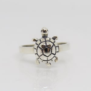 May include: A silver ring with a turtle design. The turtle is detailed with a textured shell and small legs.